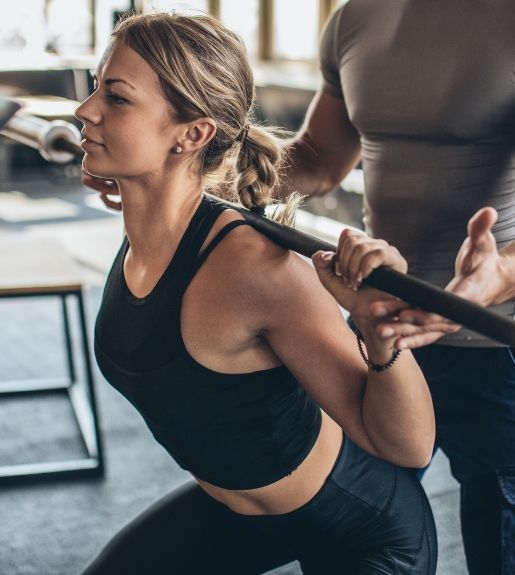 Personal training session at Powerhouse Gym Linden NJ with trainer spotting woman during squat