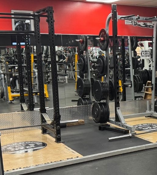 Strength training area at Powerhouse Gym Linden NJ with squat rack and weight plates
