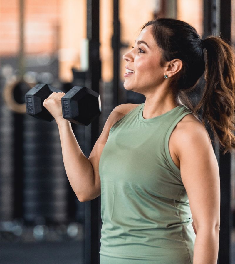 Woman lifting a dumbbell during a strength training workout at Powerhouse Gym Linden, focusing on muscle building and fitness.